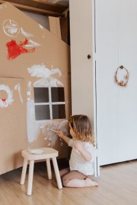 girl painting cardboard house