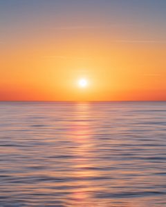 calm water with sun and orange sky